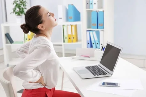 A woman stretching her back on work