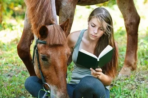 Girl reading book with horse
