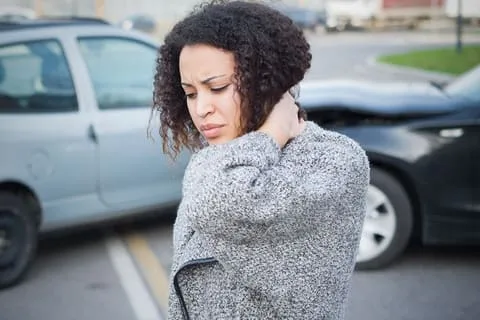 Woman holds her neck because she has whiplash after an auto accident