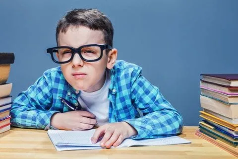 Young boy squinting while reading