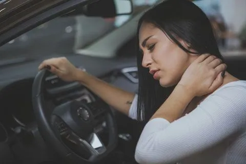 woman driving holding her neck