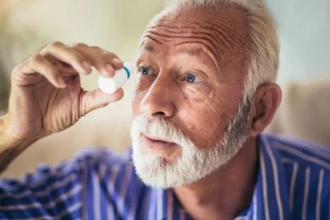 Older man using eye drops for glaucoma treatment