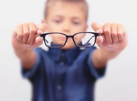 Young boy holding glasses in front of him