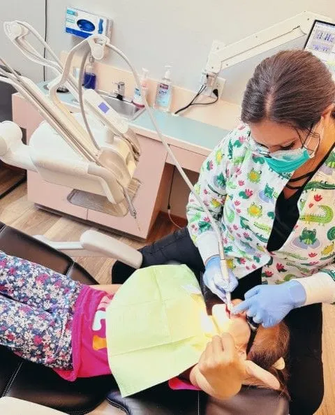 female dental hygienist cleaning young girl's teeth in exam room, teeth cleaning Salem, OR dentist