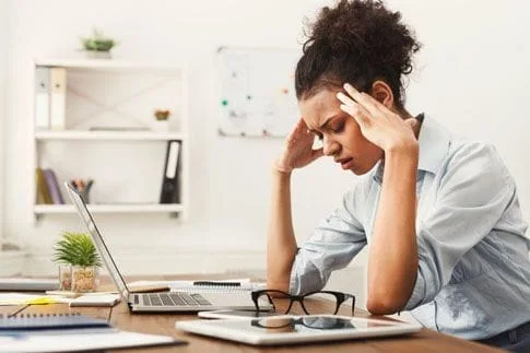 Women with headache at computer