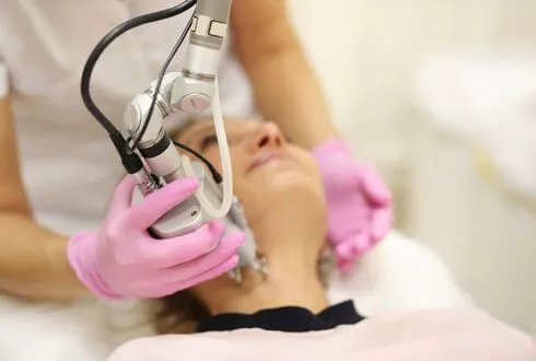 Female client receiving laser treatment for facial wrinkle reduction.