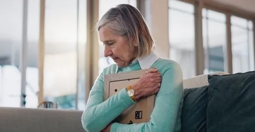 Senior woman grieving while holding photo of deceased loved one