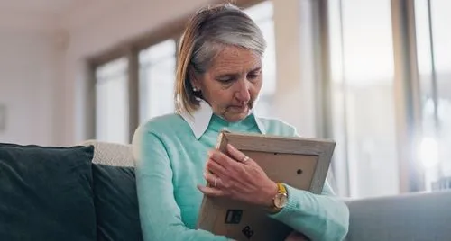 Woman grieving while holding a photo of a deceased loved one