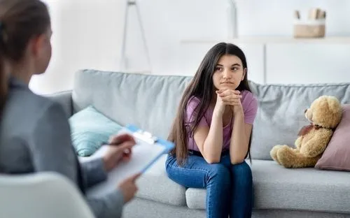 Young adolescent girl talking to a therapist on sofa