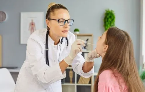 Doctor checking the throat of a young girl