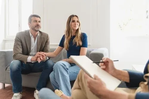 Couple talking to a therapist sitting on sofa