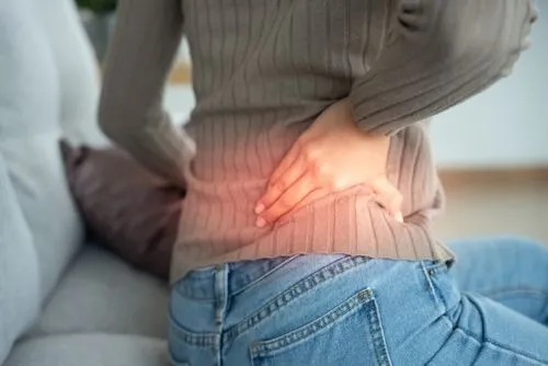 Woman suffering from back pain at home