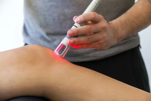 Cold laser therapy applied to client’s knee for pain relief