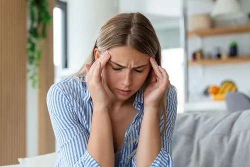A woman holding her head in pain due to a severe headache or migraine.