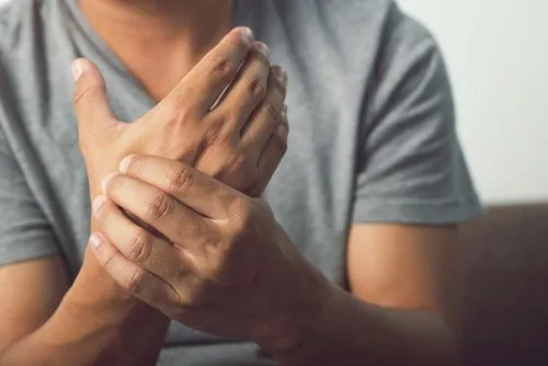 A man holding his hand in pain due to neuropathy-related nerve damage.