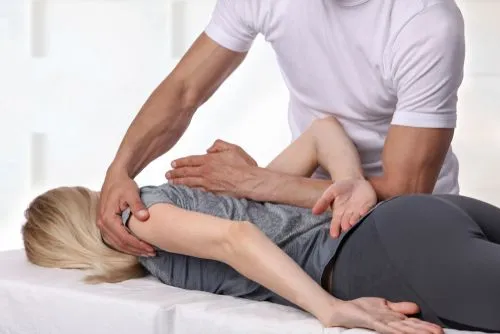 Female client receiving a chiropractic back adjustment from a chiropractor