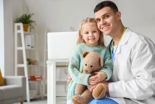 Pediatrician holding a young girl during a consultation covered by private insurance