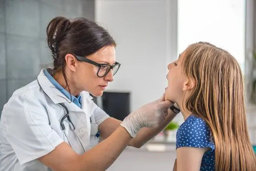 Pediatrician examining a young girl for strep throat symptoms