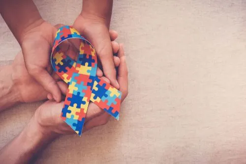 Puzzle ribbon held in hands to raise awareness for Autism Spectrum Disorder.