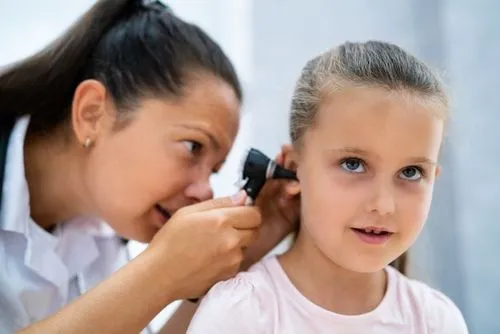 Child receiving ear examination from pediatrician