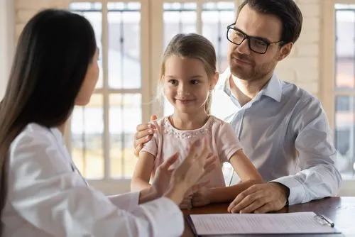 Doctor explaining a medication authorization form to a father and daughter.