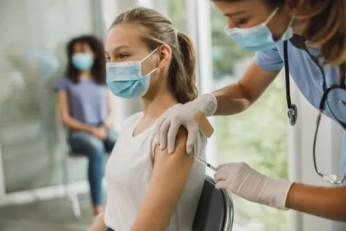 Girl receiving an immunization shot from her doctor.