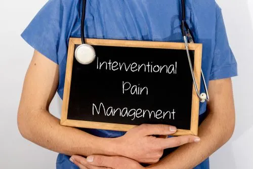 Board with "Interventional Pain Management" held by doctor