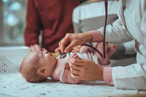 Newborn lying calmly while a pediatrician listens to the heartbeat.