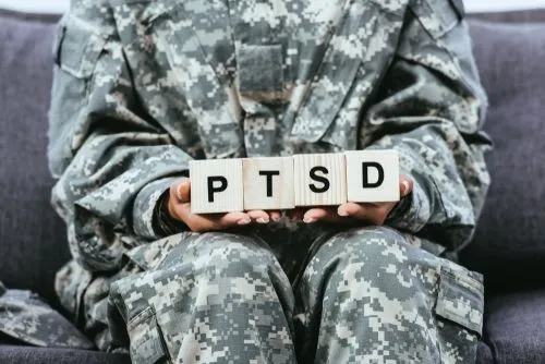 Veteran holding wooden blocks labeled PTSD to illustrate post-traumatic stress awareness