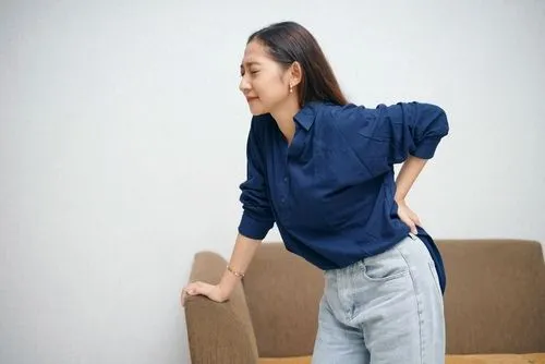 Woman suffering from back pain holding it