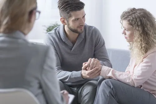 Couple holding each other's hands during marriage counseling