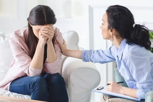 Therapist comforting a crying female client during a grief counseling session