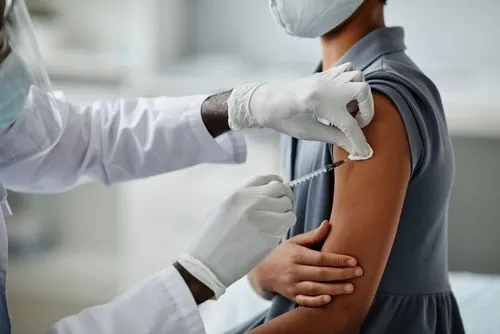 Child receiving recommended immunization from healthcare professional.