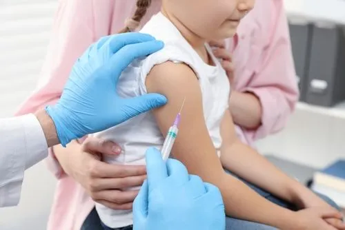 Healthcare provider preparing a vaccine injection for a young patient