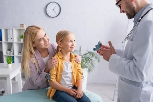 Doctor teaching a young girl how to use inhaler with her mother