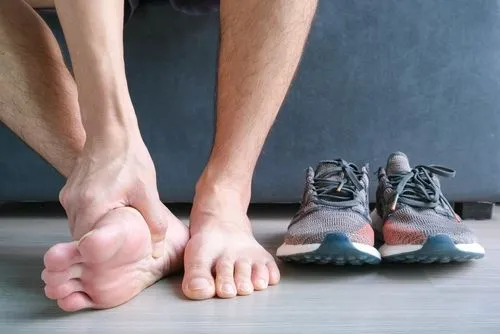 Person suffering from Plantar fasciitis with shoes beside it