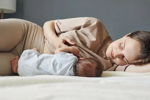 Young woman having a lactation to her child on bed
