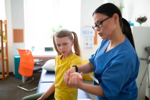 Pediatrician examining a child's muscles and joints during a sports physical
