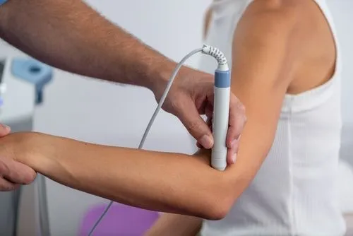 Chiropractor treating elbow of patient with laser therapy in regenerative medicine