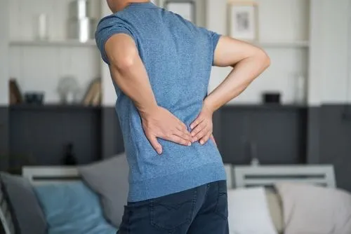 Man holding his lower back while experiencing pain at home