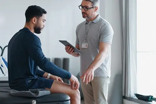 Chiropractor consulting with male client on knee pain