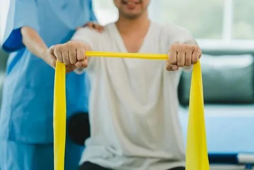 Man using resistance band for rehabilitation during therapy session