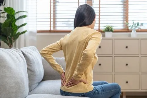 Woman suffering from low back pain at home