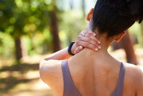 Female patient holding her neck in discomfort, back view