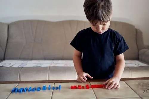 A young boy playing alone on tanble with bloks
