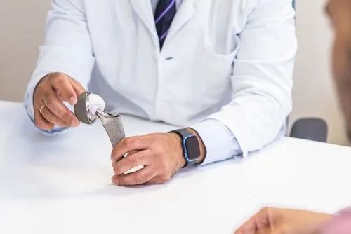 Orthopedic surgeon discussing joint replacement with model