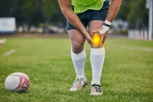 Rugby player holding his injured knee during a match.