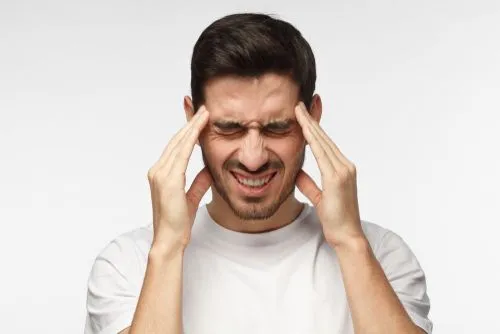 Male patient showing signs of severe headache on a white background
