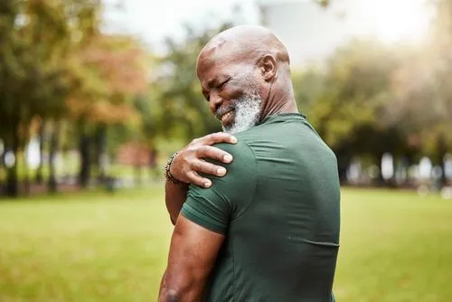 Senior man holding his shoulder in pain outdoors