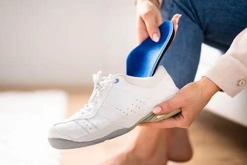 Woman inserting custom foot orthotic into shoe